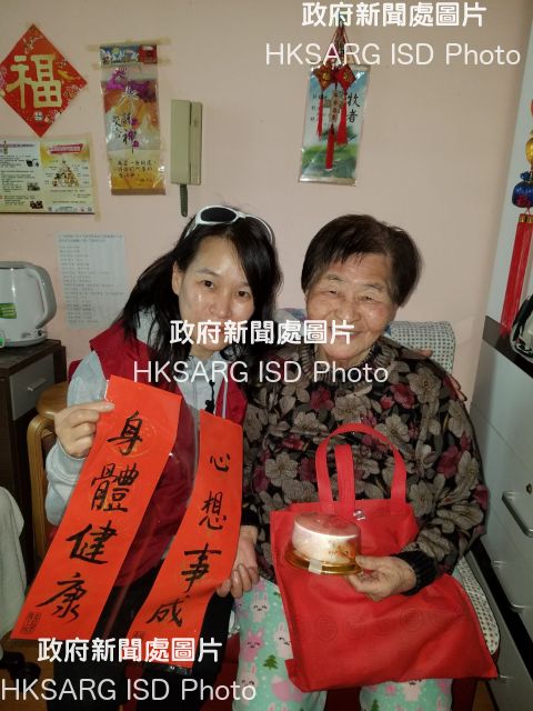 The Housing Department (HD) Volunteers Corps visited elderly tenants at Ming Tak Estate, Tseung Kwan O, last Saturday (February 10). Photo shows a member of the HD Volunteers Corps giving an elderly tenant festive gifts.