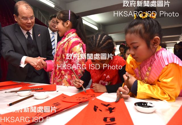 The Chief Secretary for Administration, Mr Matthew Cheung Kin-chung, visited a shared service place operated by the Lok Sin Tong Benevolent Society, Kowloon today (February 14) and observed ethnic minority children preparing spring couplets. Photo shows Mr Cheung (first left) chatting with an ethnic minority child.